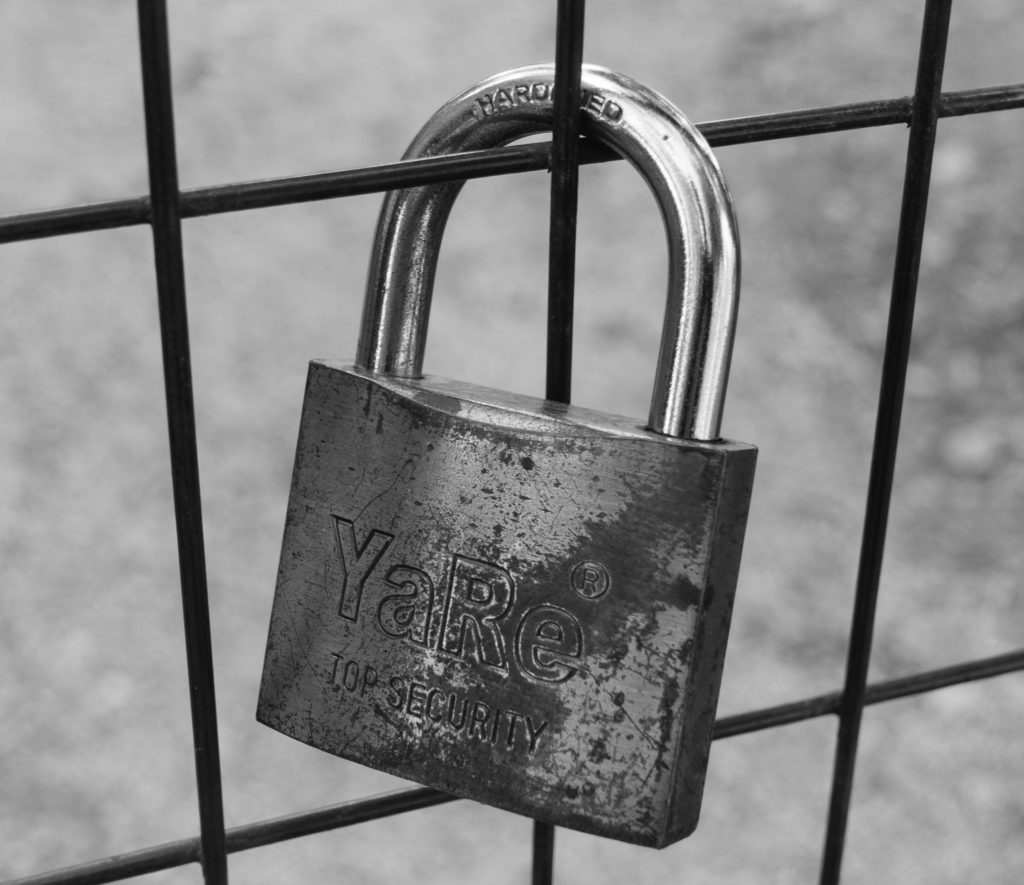 A locked padlock on a wire fence. 