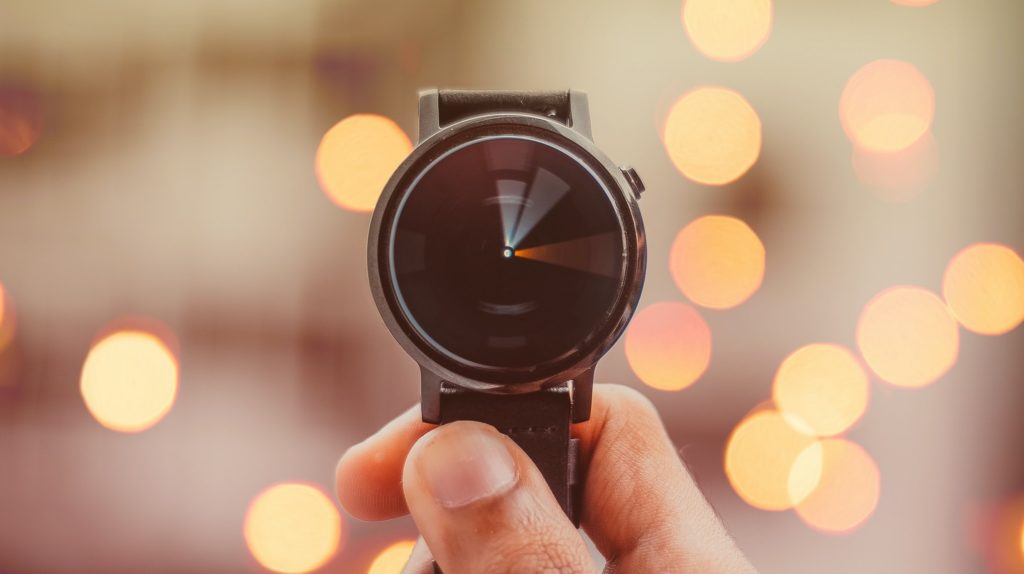 Hand holding a watch, with a time-lapsed movement of the hands to indicate speed. 