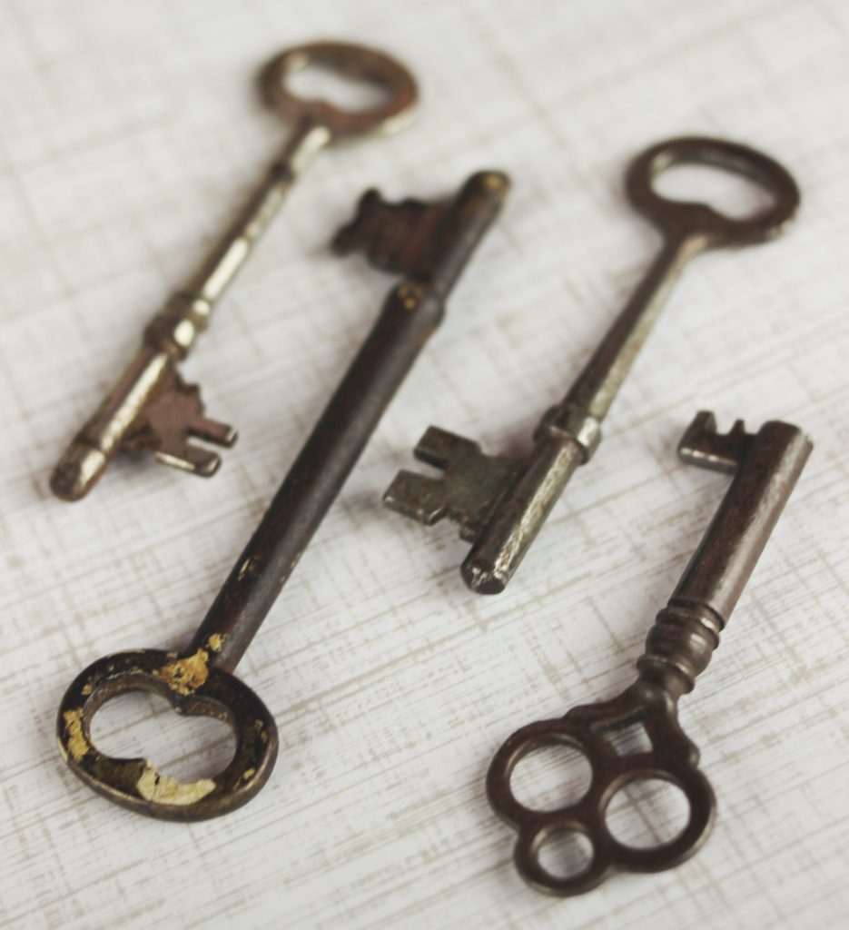 Four old keys lying on a linen tablecloth.