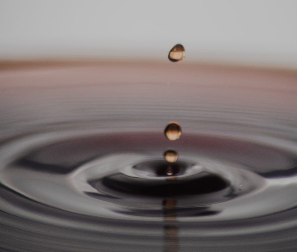 Image of three drops of liquid falling into a concentric circles of rings in a container. 