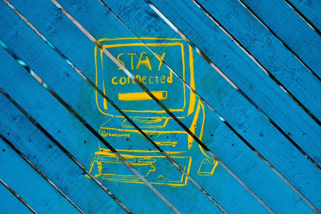 Image of a computer sketched in chalk on blue-painted wooden slats, with the message, 